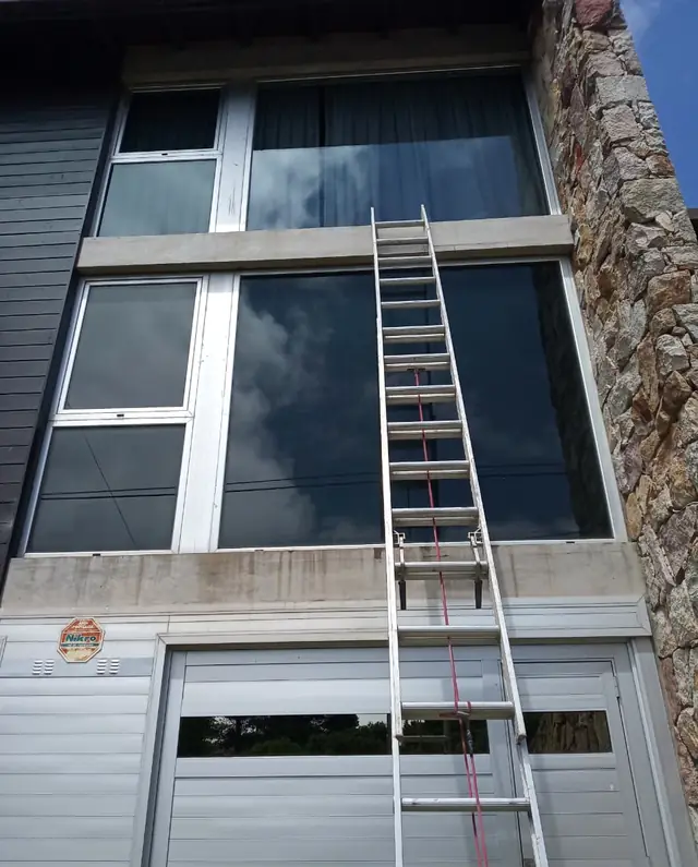 Escalera apoyada en una fachada para limpiar ventanas altas